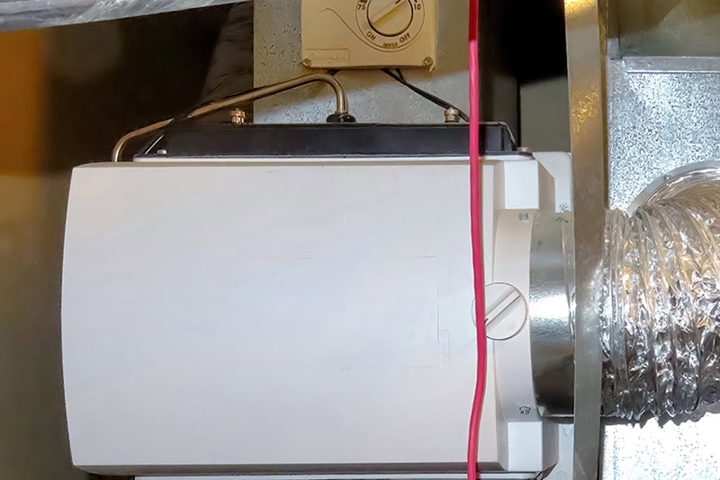 A whole-house bypass humidifier unit mounted on metal HVAC ductwork.