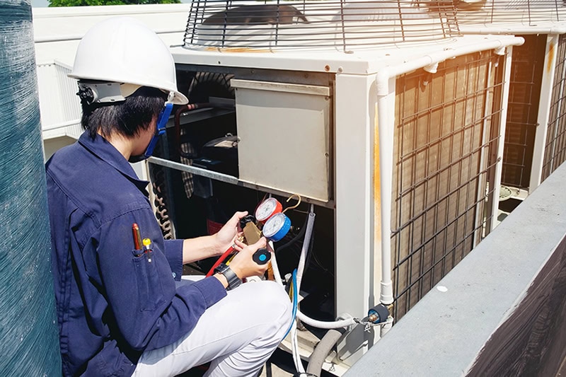 Why Is a Commercial AC Tune-Up Important? A technician fixing an air conditioning unit.